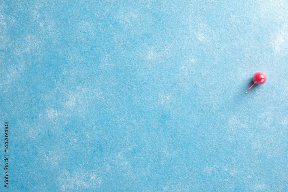 Poster Bright red push pin secured into a pastel blue corkboard, casting shadows that enhance the overall depth with clear areas for additional content or notes