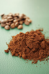 Ground coffee and whole beans on a green surface