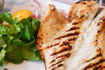 Grilled fish served with fresh greens and lemon slice