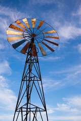 Old windmill against a blue sky with white clouds, close-up
