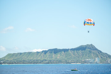 Parasail with colorful chute floats over the Pacific Ocean near Diamond Head, captured March 15, 2019 in Honolulu, Hawaii, USA