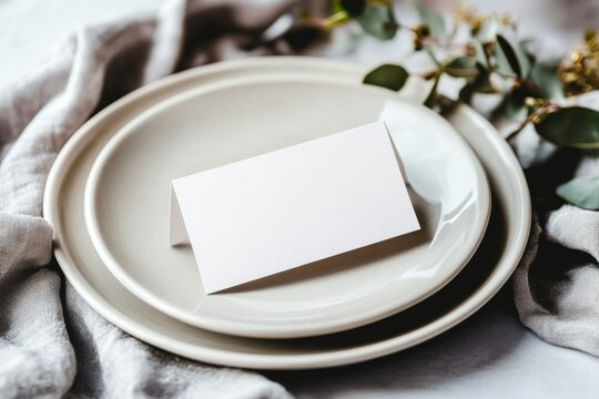 Elegant blank table name card mockup on dinner plate with foliage  