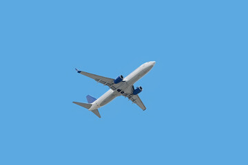 Bottom view of passenger plane taking off in blue sky