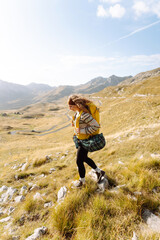 Rear view of joyful tourist in hiking clothes feeling freedom with mountain view. Young woman hiker hiking on hill. Freedom, adventure concept.