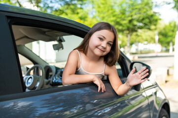 Naklejka premium Girl feeling cool and happy during road trip as passenger in vehicle on vacation