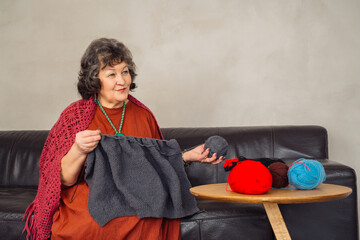 A woman enjoys knitting in her living room, surrounded by colorful yarns and crafting materials in...