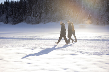 Three people walking through sunlit snow in Tyrol