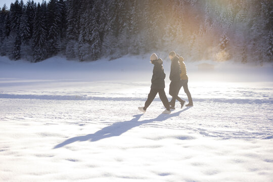 Three people walking through sunlit snow in Tyrol