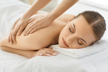 Indoor shot of relaxed woman enjoying spa treatment in salon, getting massage for back, has body...