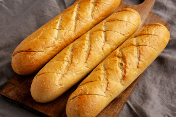 Homemade French Baguette with Garlic Filling on a wooden board, side view.