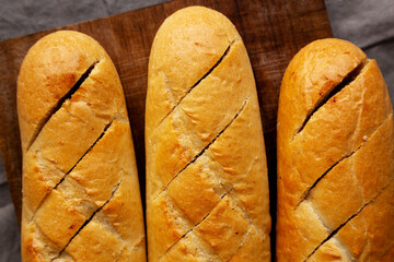 Homemade French Baguette with Garlic Filling on a wooden board, top view.