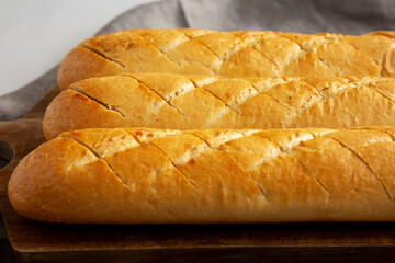 Homemade French Baguette with Garlic Filling on a wooden board, side view.