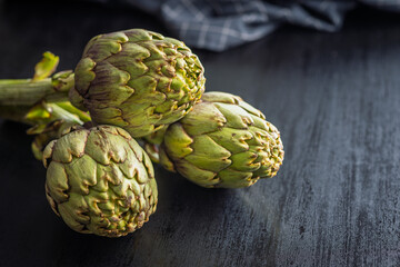 Fototapeta premium Ripe artichokes plant on black table.
