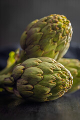 Ripe artichokes plant on black table.