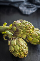 Fototapeta premium Ripe artichokes plant on black table.