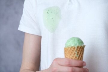 Close up melting mint ice cream in waffle cone in the background dirty stain on white clothes....