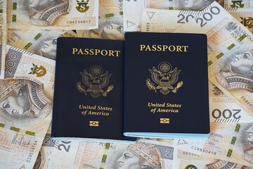 Dwa paszporty amerykańskie na tle porozrzucanych banknotów. Amerykańskie dokumenty i papierowa gotówka. © Adam