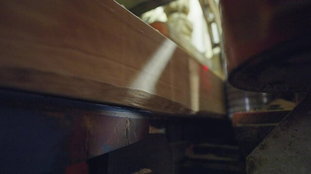 Machines inside a factory prepare wooden bars, shaping and processing them for use or transport.