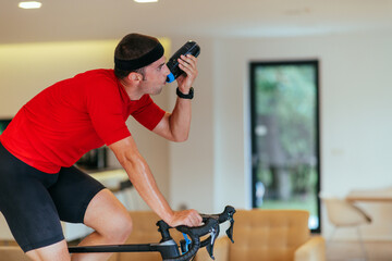 A triathlete riding a triathlon bike on a machine simulation in a modern living room. Training...