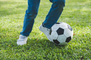 Obraz premium Little boy playing football in the garden with morning sunrise