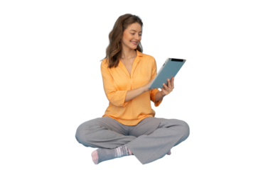 Smiling young woman sitting with legs crossed using digital tablet, isolated on transparent background