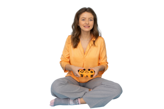 Happy young woman sitting cross-legged holding a controller and playing videogames, isolated on transparent background - Powered by Adobe
