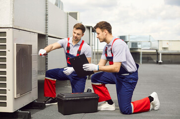 Male engineers and electricians working together to installing, maintaining, or repairing an air...