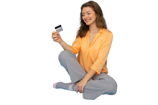 Smiling young woman holding a credit card while sitting with crossed legs on a transparent background