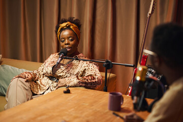 African American woman speaking in microphone and answering questions during interview in studio