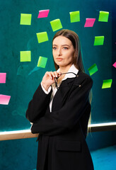 Businesswoman pondering success. A businesswoman stands in an office with colorful sticky notes...