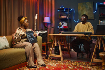 Woman sitting on sofa in studio and talking about the music record during podcast