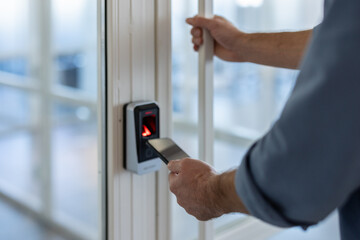 A person is using their smartphone to access an office door using a security system.
