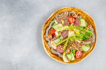 beef steak medium rare, fresh greens and vegetable salad on a light background, top view. copy space