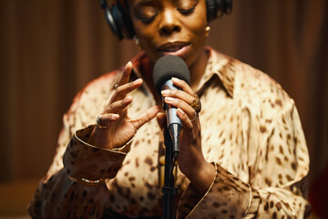 African American performer in headphones performing with her song during podcast