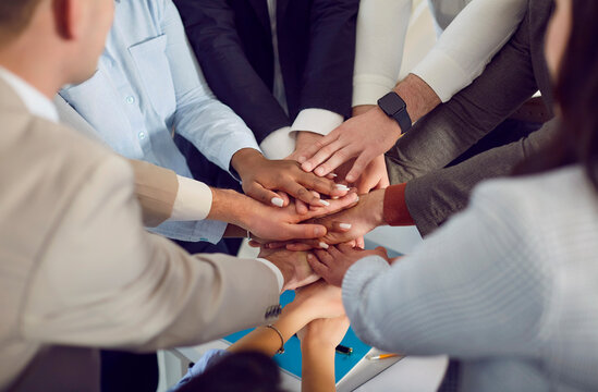 Business multicultural people join hands and place them on top of each other close-up. Concept solidarity and team support, teamwork of colleagues, community, corporate unity, merger