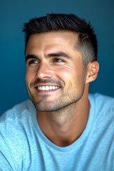 Obraz premium Blue solid background. Elegant men's crew cut haircut - midlife white man with black hair. Creative art of style for aging men. A dynamic male posing with grace and charm.