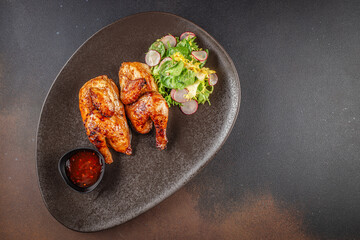 Fried chicken with fresh herbs. Tobacco chicken on a dark background. Georgian dish. top view. copy space.