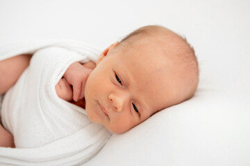 a newborn baby is lying in a diaper on a bed on a white isolated background, a place for text, a small baby boy is sleeping sweetly, a close-up portrait