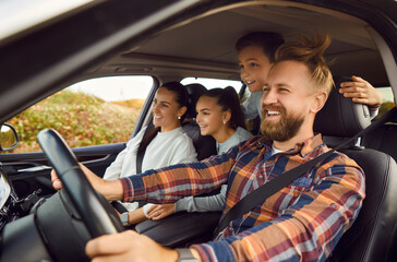 Portrait of happy laughing smiling family of four with children riding in modern car traveling by...