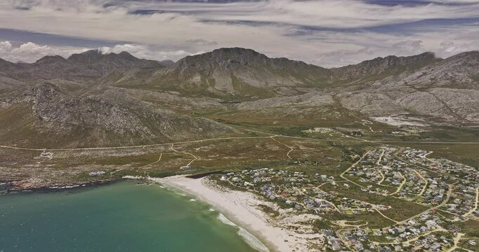 Pringle Bay South Africa Aerial v2 high flyover white sand beach, capturing picturesque coastal residential townscape against a backdrop of rugged mountains - Shot with Mavic 3 Pro Cine - Jan 9th 2024