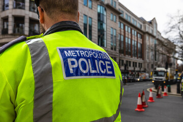 Metropolitan Police officer wearing high visibility jacket patrolling London street