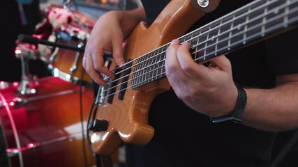 Close-up, unrecognizable musician bassist plays bass guitar at concert, party, event, wedding. Hands of bassist play musical instrument skillfully actively moving to beat of music and pressing notes