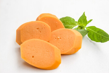 raw sausage slices with basil leaves isolated on white background