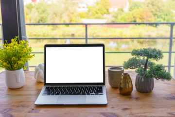 Laptop computer with white, transparent screen on wooden desk on wide window background. Office workspace, workplace in cafe or home. Mockup, template with copy space