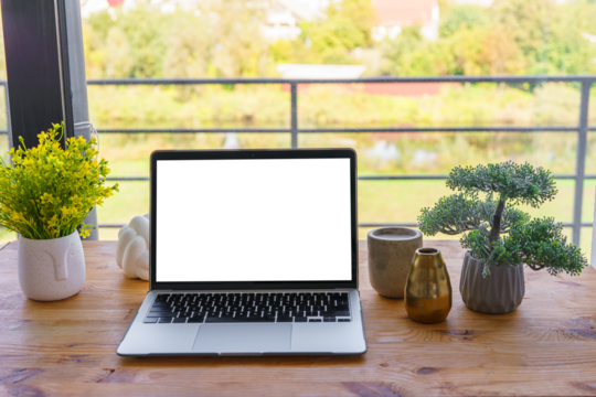 Laptop computer with white, transparent screen on wooden desk on wide window background. Office workspace, workplace in cafe or home. Mockup, template with copy space