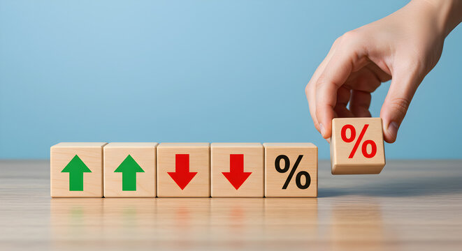 Hand Arranging Wooden Blocks with Up and Down Arrows and Percentage Symbols on Wooden Table Against a Light Blue Background