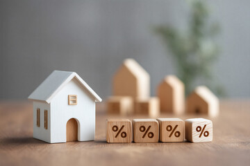 Miniature house alongside blocks with percentage symbols, symbolizing housing market or interest rates.