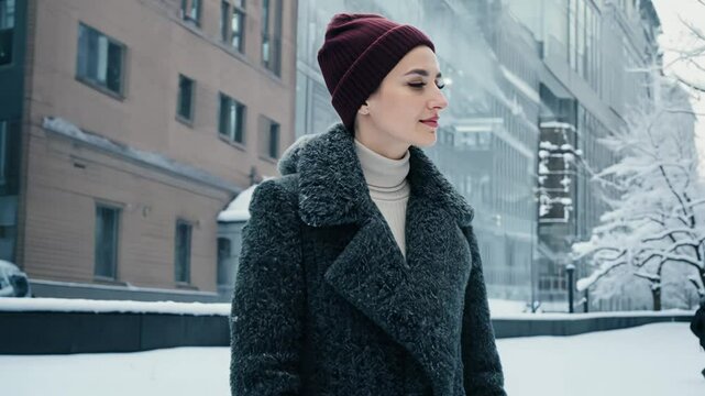 Woman model wearing a stylish tailored wool coat in a winter city scene, camera pans with key light. Concept of urban winter fashion
