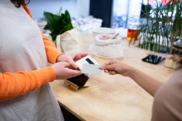 Customer paying with credit card using nfc technology on pos terminal in zero waste store