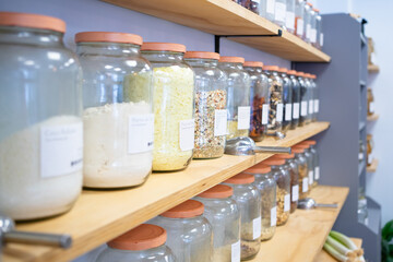 Glass jars with bulk food items displayed on wooden shelves in zero waste shop